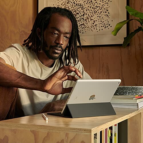 Man using a tablet at home with a pencil on the table.